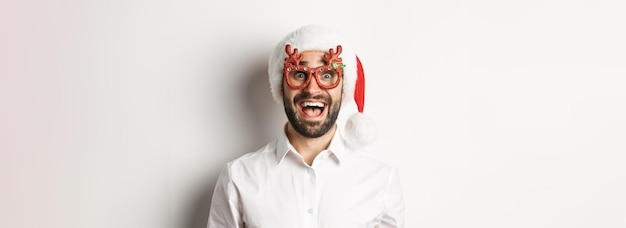 Free Photo closeup of excited bearded man in christmas glasses and santa hat looking amazed at promo offer wint