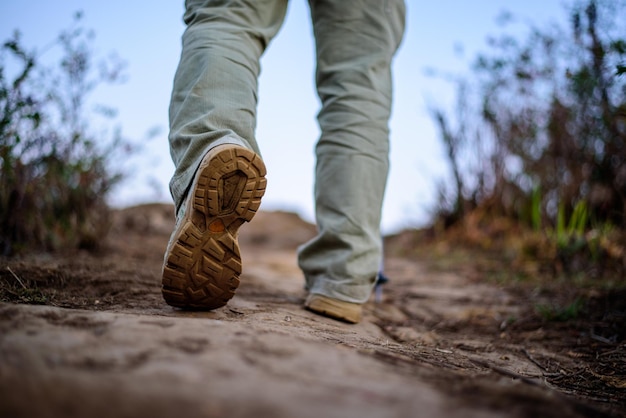 Closeup feet Hiker man wearing boots to travel walking in a green forest Travel vacation and hiking concept