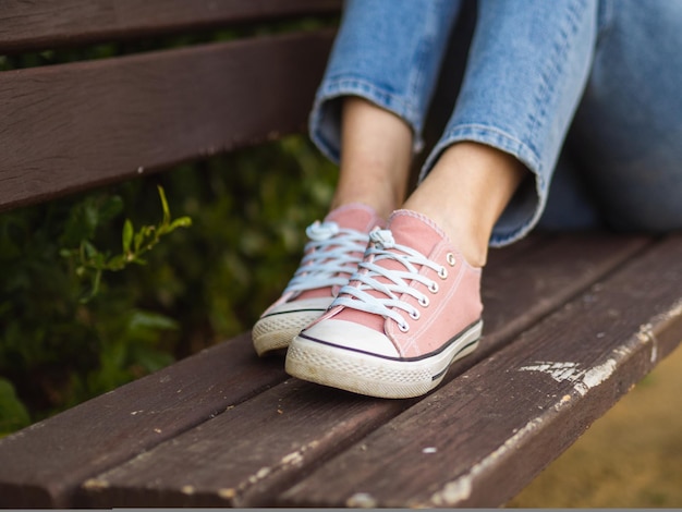 Closeup of female legs in casual pink sneakers; spring footwear