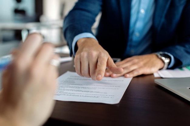 Closeup of financial advisor pointing at place of signature on a contract