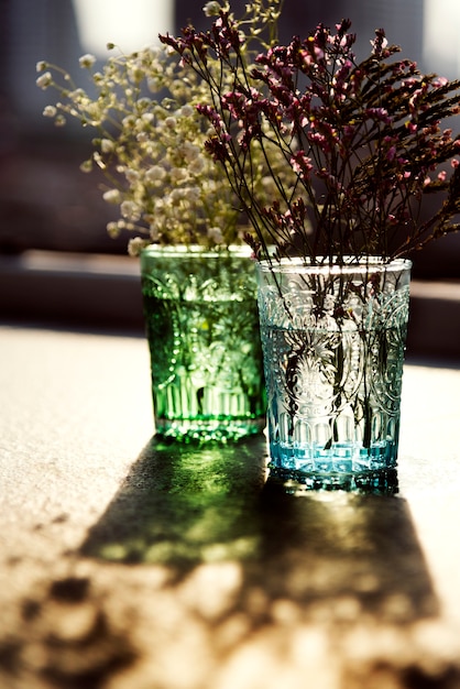 Free photo closeup of flowers in glass vases on wooden table