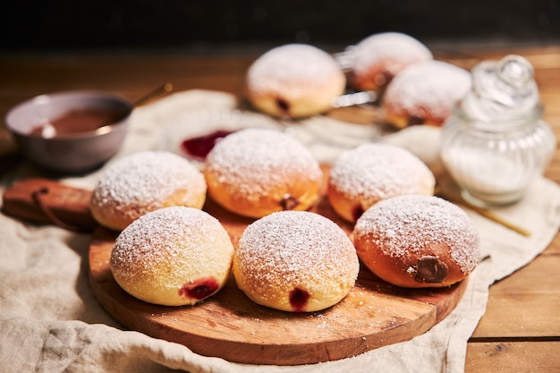 Closeup of fluffy doughnuts filled with jam on a tray on the table under the lights