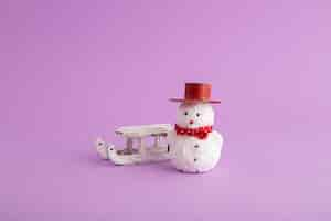 Free photo closeup of a funny snowman and a christmas sleigh in the purple background