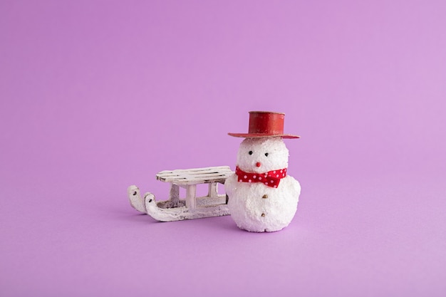 Free Photo closeup of a funny snowman and a christmas sleigh in the purple background