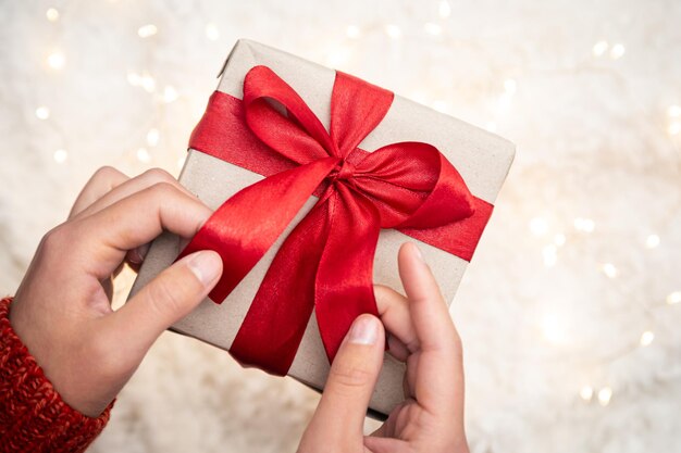 Closeup gift box with red ribbons in female hands top view