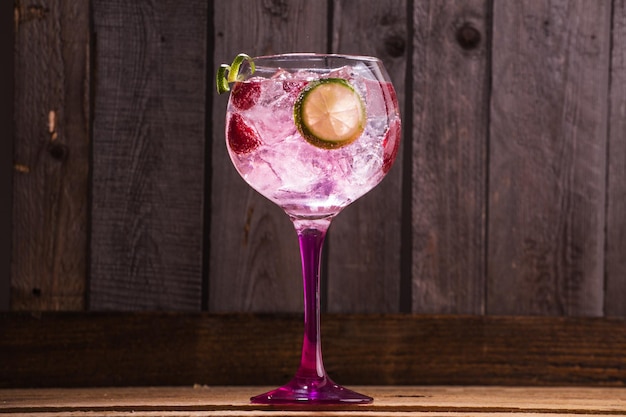 Free photo closeup of gin and tonic with ice and raspberries against a wooden background