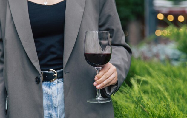 Closeup a glass of red wine against the background of green bushes