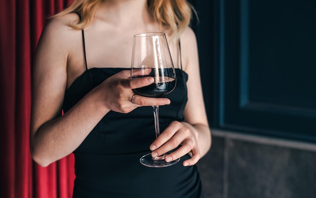 Closeup a glass of wine in the hands of a woman in an evening dress