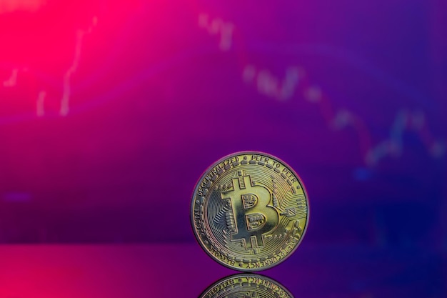 Free photo closeup of a golden bitcoin on a pink and blue reflective surface and the histogram