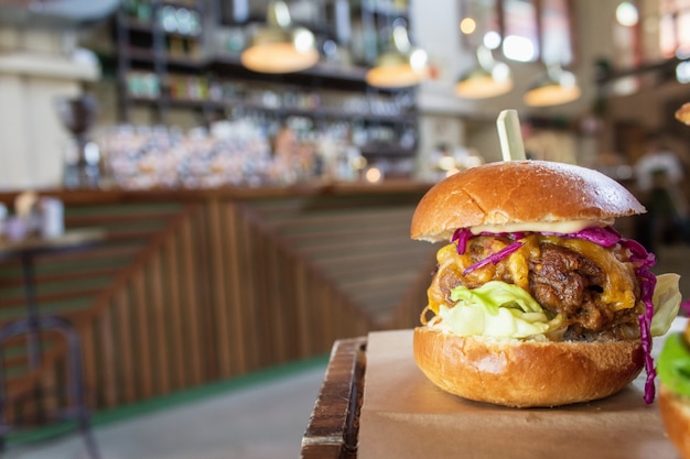 Closeup of a hamburger in a wooden tray with a blurred background