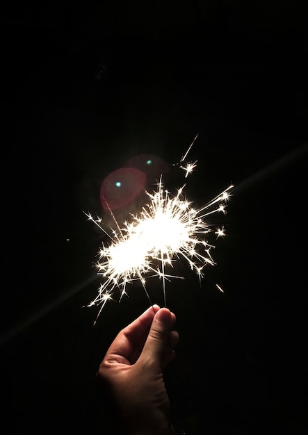 Free photo closeup of hand holding sparkler with black background