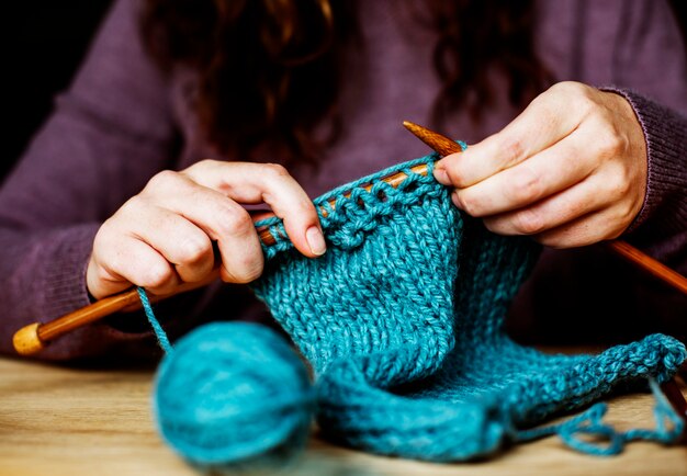 Closeup of hands knitting on wooden table