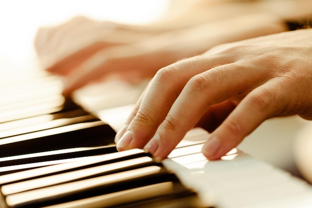 Closeup of hands playing piano music and hobby concept