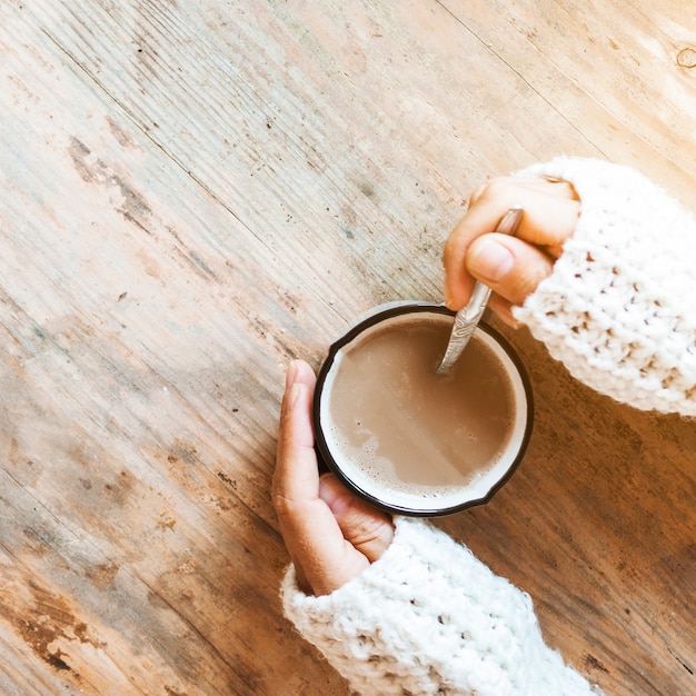 Closeup hands stirring coffee in mug