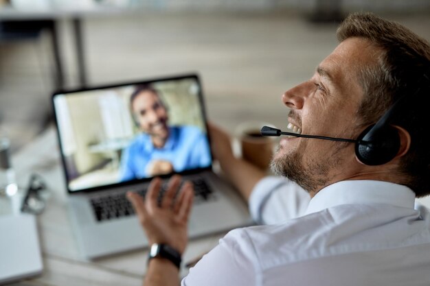 Closeup of happy entrepreneur using laptop while talking online with his business colleague