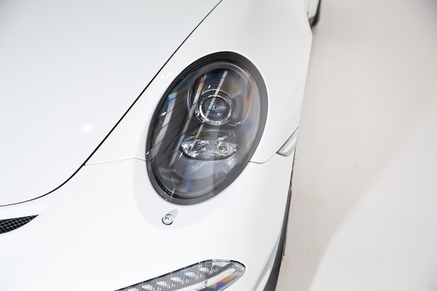 Free photo closeup of the headlight of a white luxury car under the lights against a grey background