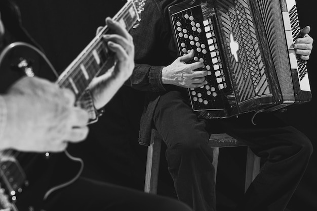 Free Photo closeup image of male hands playing guitar and accordion black and white photography retro culture