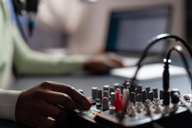 Closeup of influencer woman checking sound of professional mixer while recording online vlog talking with subscribers using microphone. Content creator filming video for social media. On air talk show