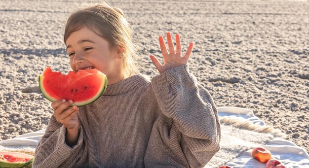 Closeup little girl eats watermelon on the beach