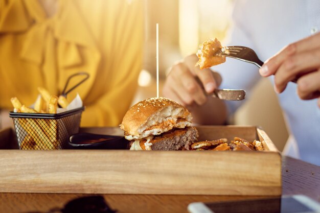 Closeup of man eating cheeseburger on a lunch with his girlfriend