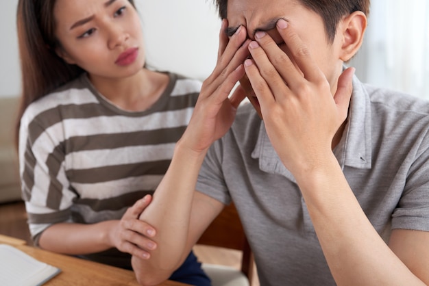 Closeup of man facing financial challenges comforted by his wife