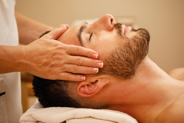 Closeup of man getting head massage and relaxing with eyes closed at the spa