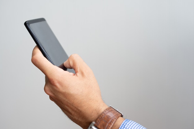 Free photo closeup of man holding smartphone and touching its screen