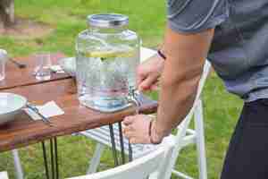 Free photo closeup of man pouring lemonade from dispenser outdoors