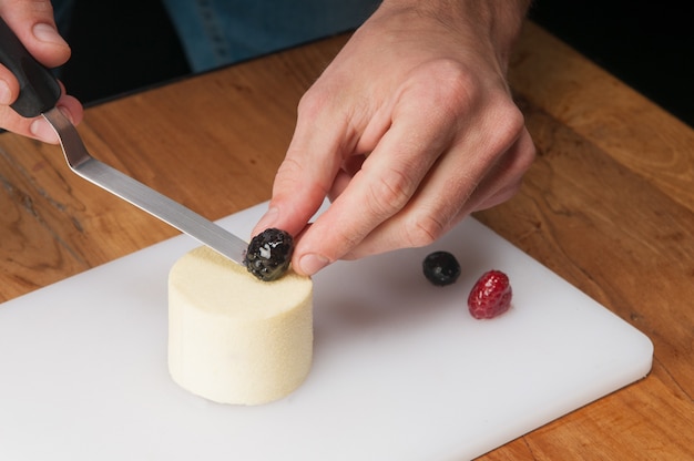 Closeup of man putting berry on peace of ice-cream at table