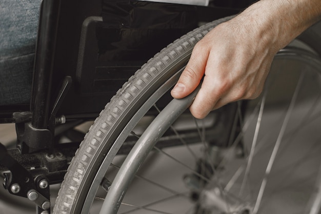 Free photo closeup of a man's hand on the wheel of his wheelchair.