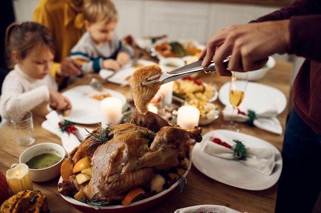 Closeup of man serving turkey meat during family meal on Thanksgiving