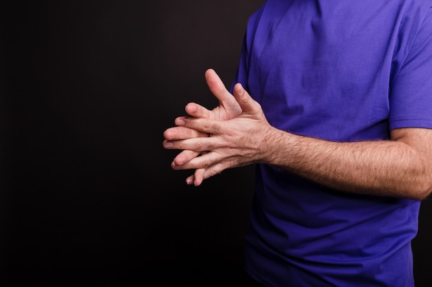 Free photo closeup of a man using a hand sanitiser against a black background - covid-19