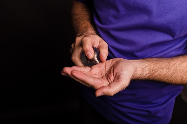 Closeup of a man using a hand sanitiser on black