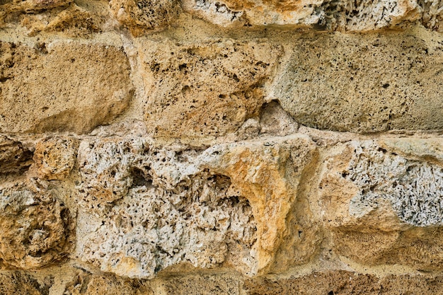 Free photo closeup of the masonry of an ancient soft sandstone wall that has been eroded by time natural stone idea for background or interior