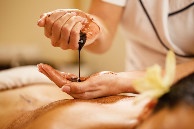 Free photo closeup of massage therapist pouring hot chocolate in her hands before spa treatment