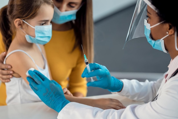 Closeup of a pediatrician giving vaccine to a little girl at the clinic