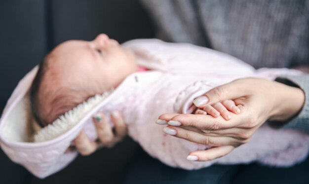 Closeup of a pen of a newborn baby girl in moms hand