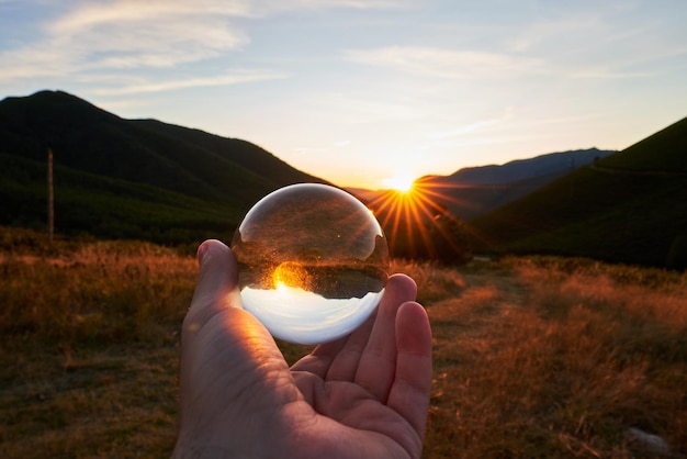 Free Photo closeup of a person holding a crystal ball with the surroundings reflecting on it under the sunlight