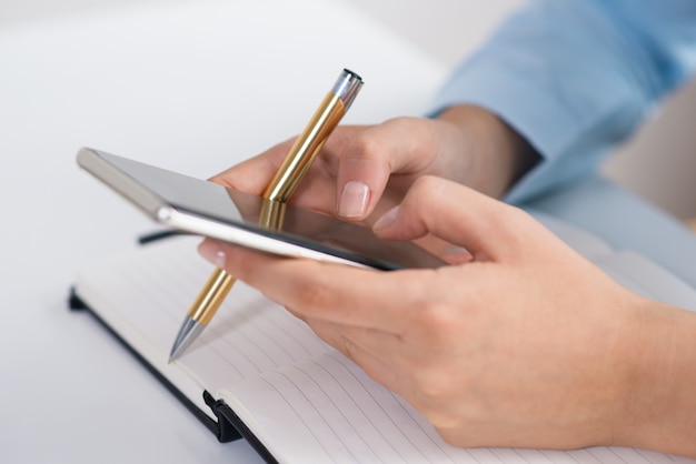 Closeup of person texting on smartphone and working at desk