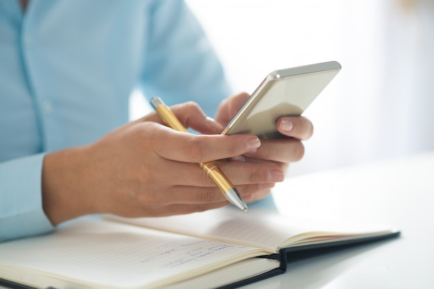 Closeup of person using smartphone and working at table