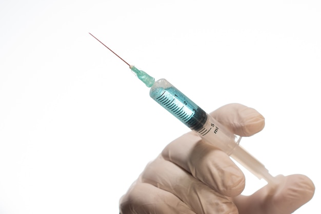 Free Photo closeup of a person with a latex glove holding a needle syringe isolated on a white background