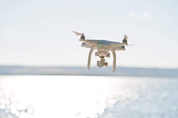 Closeup photo of a drone flying over the lake and taking pictures of it