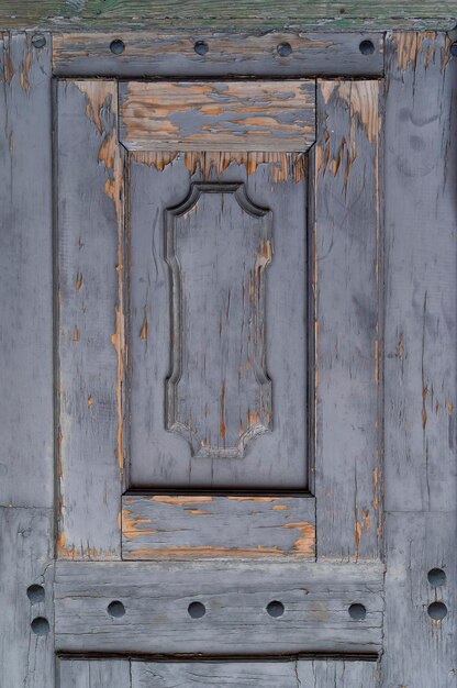 Closeup photo of old wooden door with peeling gray paint