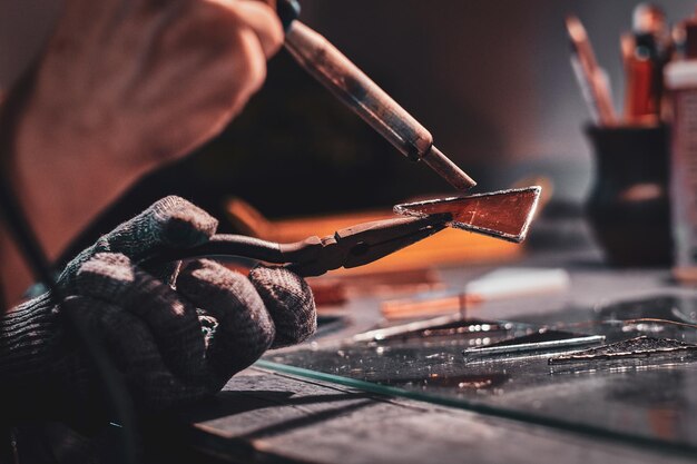 Closeup photo shoot of of soldering using pliers and peace of glass.