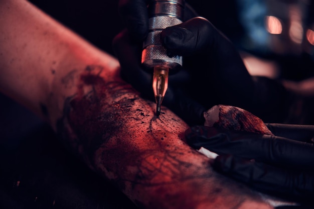 Closeup photo shoot of tattoo making, artist is working with tattoo machine on customer's hand.