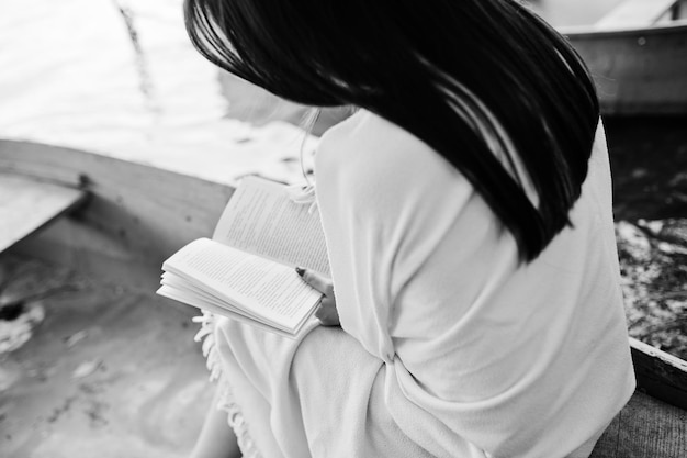 Free photo closeup photo of woman's back while reading a book in a boat black and white photo