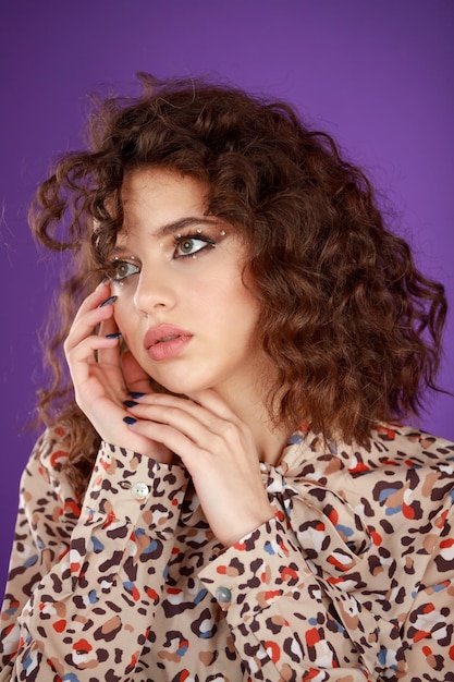 Closeup photo of a young curlyhaired girl put her hands to her chin and loking away High quality photo