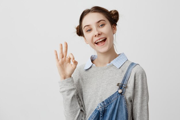 Closeup picture of good-looking woman showing alright with fingers laughing in rejoice. Adult female coach being glad for good results expressing happiness with gestures. Body language