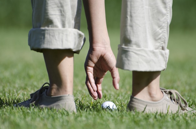 Closeup picture of a human taking a white gold ball in the field