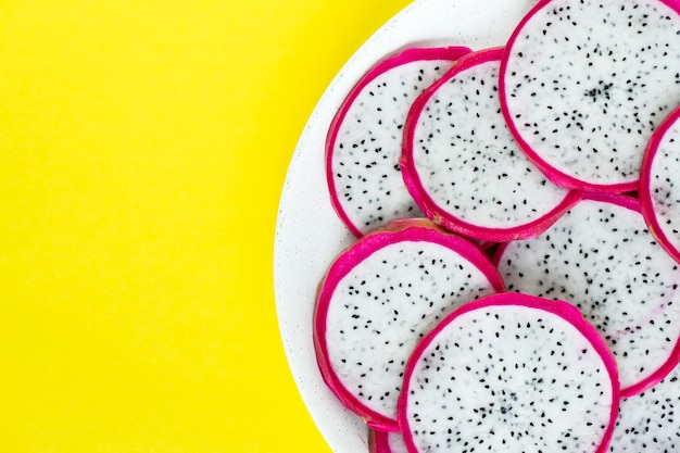 Free Photo closeup of a plate of dragon fruit slices on yellow background